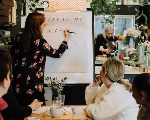 Toronto Calligraphy Instructor demonstrates modern calligraphy for a group of students in a flower shop and cafe.